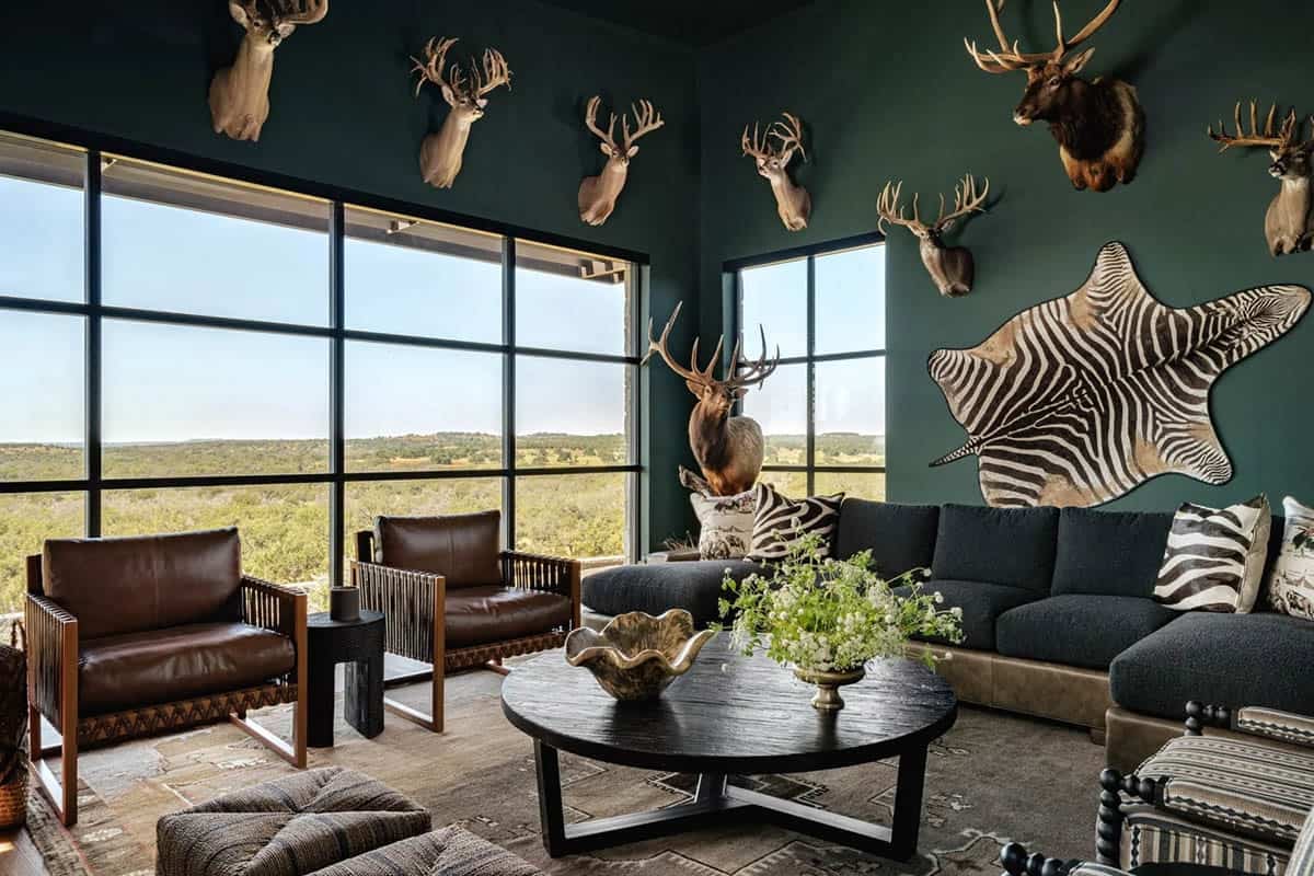 Hunter's lounge with dark green walls, mounted trophies and floor-to-ceiling Hill Country views