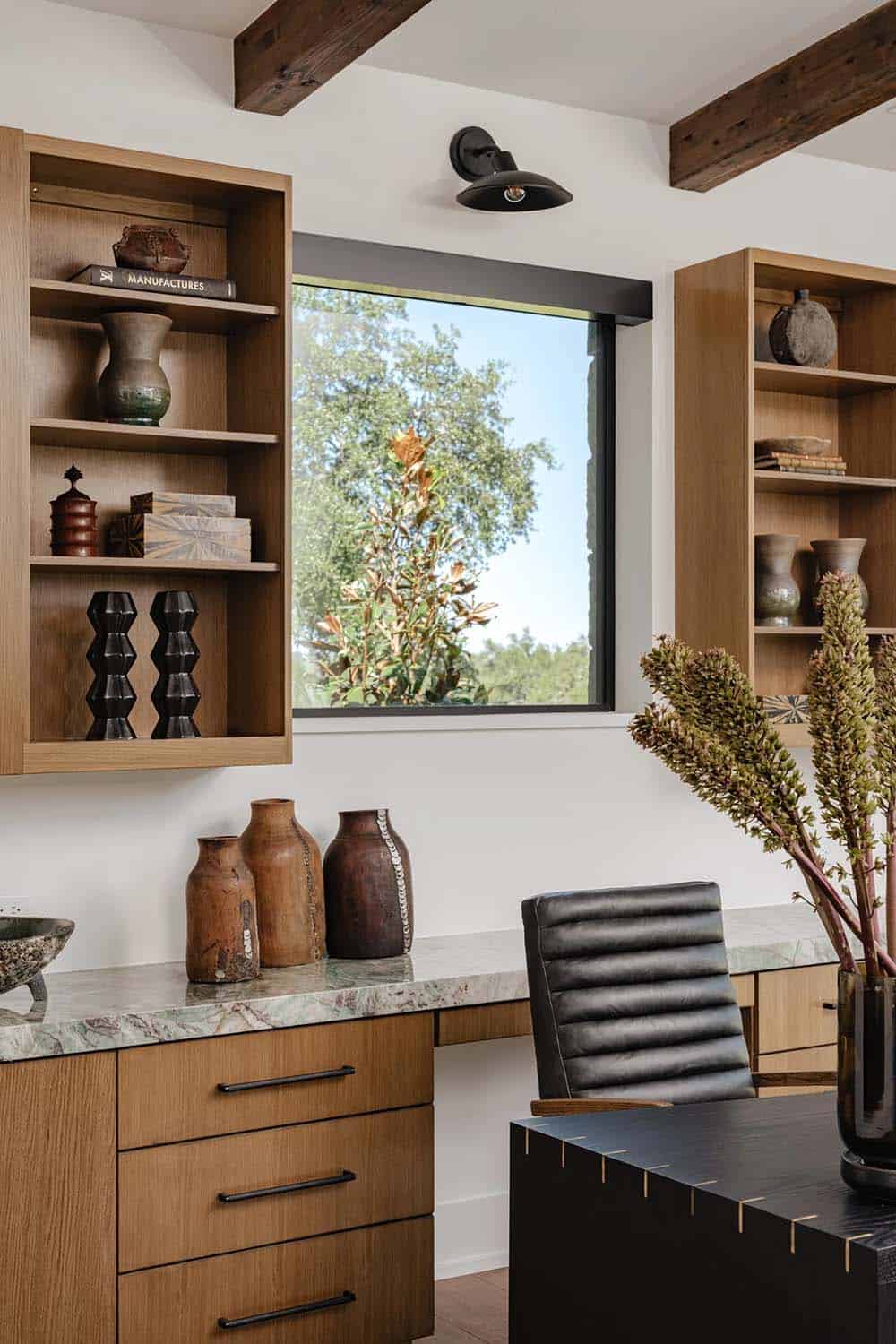 Home office detail with oak shelving, ceramic vases and black wall sconce