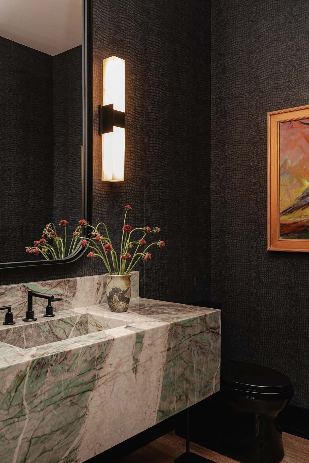 Dramatic powder bath with dark crocodile wallpaper, green marble sink and art