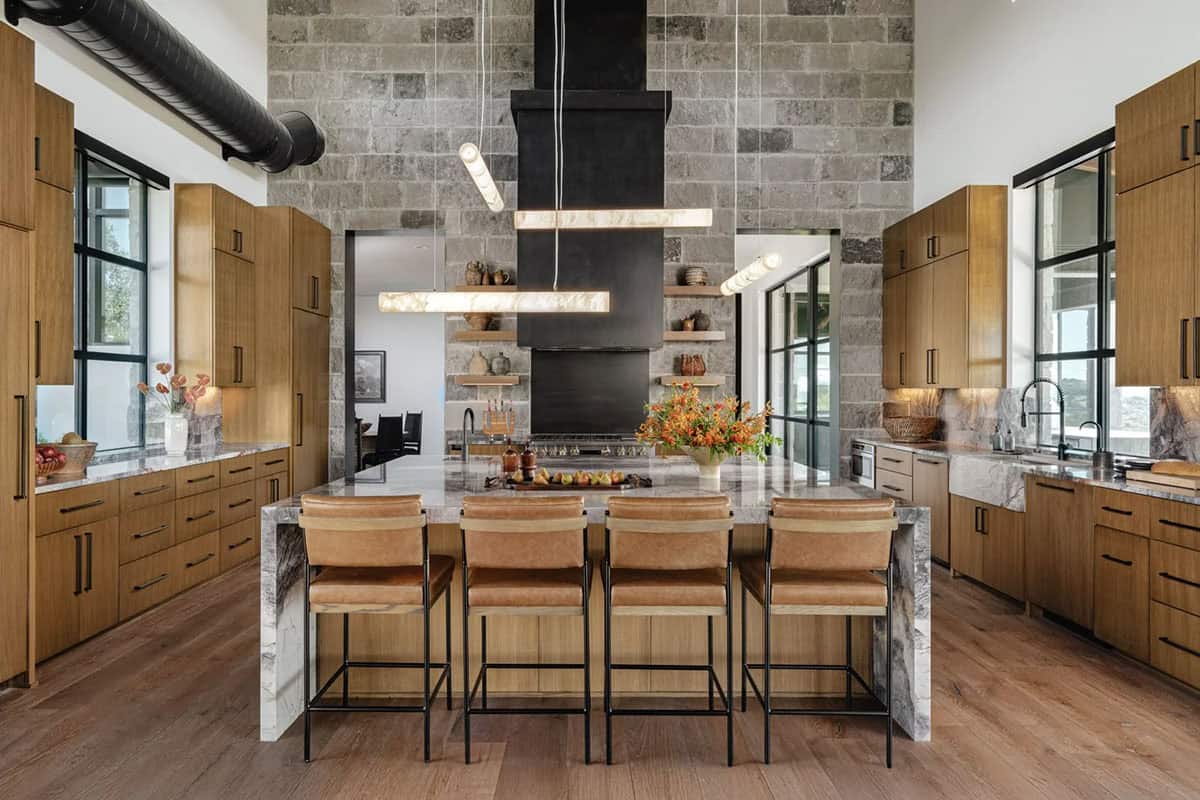 Chef's kitchen with marble island, oak cabinetry, stone walls and alabaster pendant lights