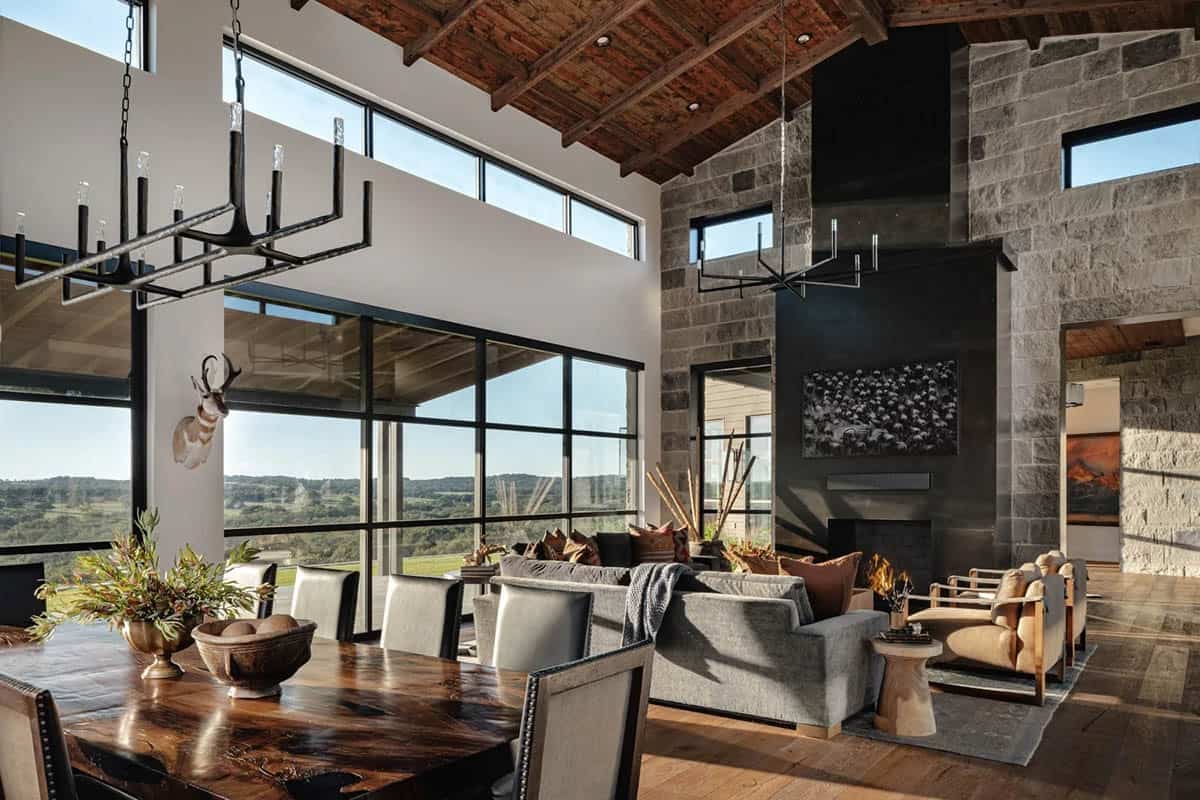 Open plan living and dining room with reclaimed wood ceiling, stone fireplace and panoramic Hill Country views