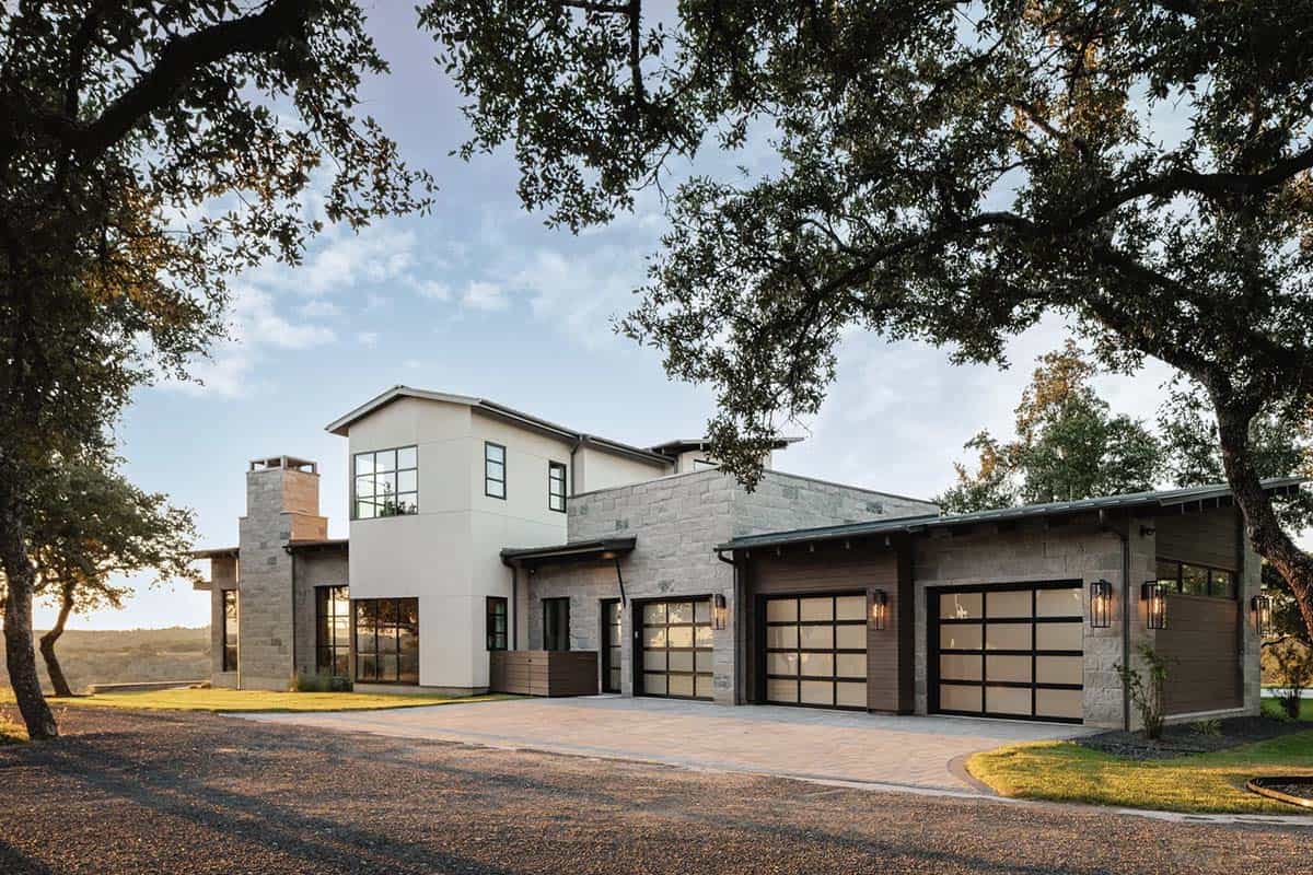 Contemporary Hill Country ranch home front elevation at dusk framed by live oak trees