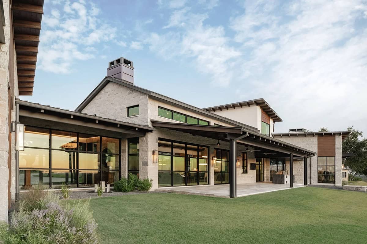 Rear exterior of Hill Country ranch home at dusk with covered patio and outdoor kitchen