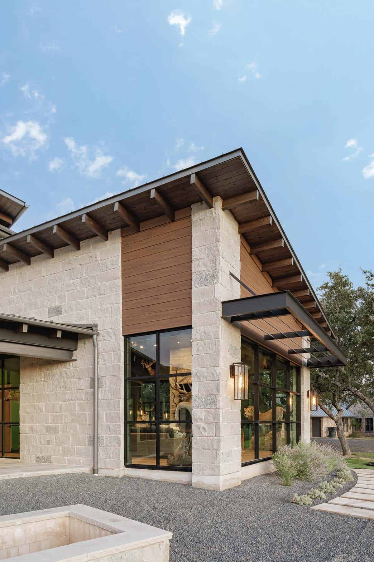 Close up of limestone exterior corner with wood ceiling, steel frame windows and wall sconce
