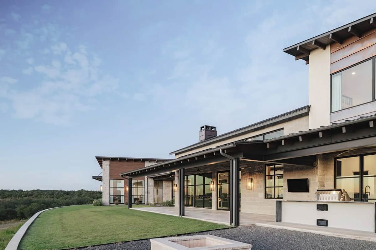 Covered outdoor living area with outdoor kitchen and sweeping Hill Country views at dusk