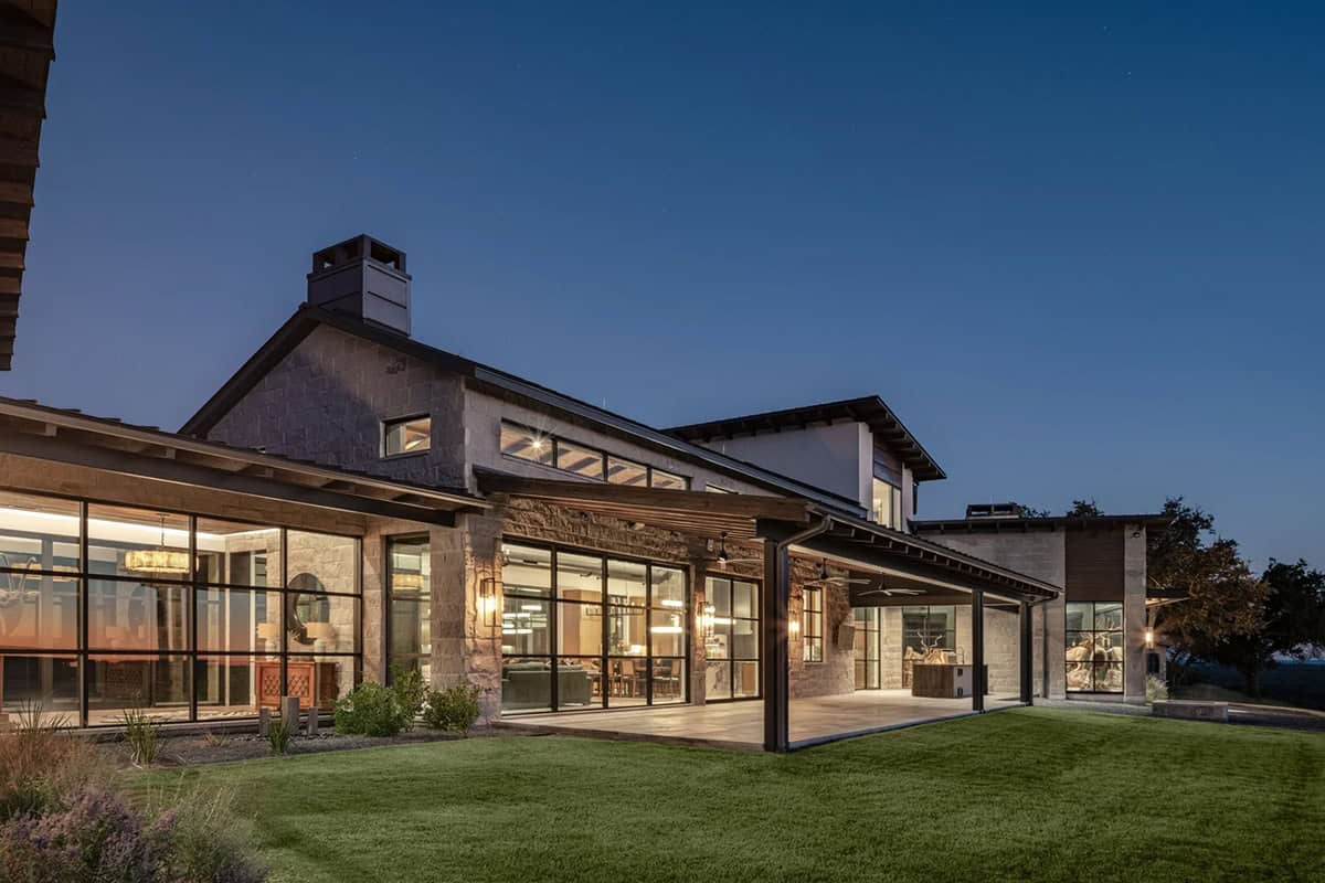 Contemporary Hill Country ranch home exterior at night with glowing steel frame windows