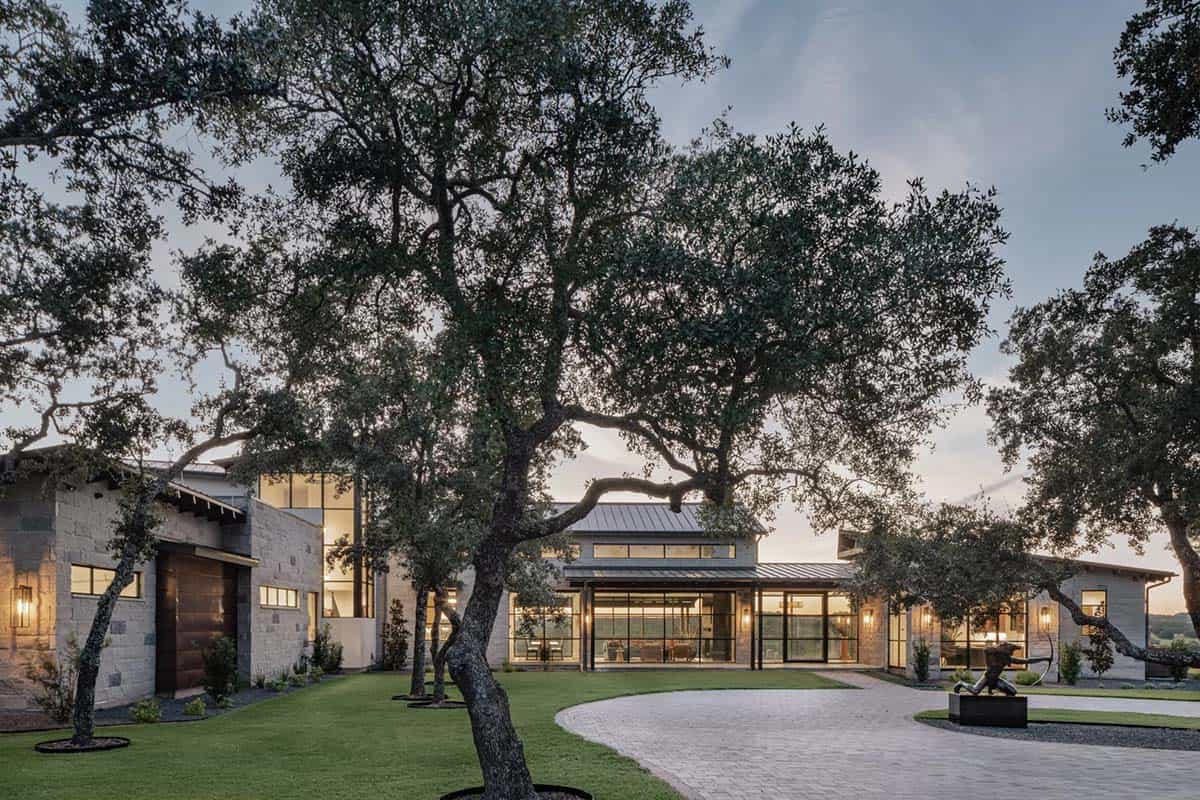 Twilight view of circular driveway with mature oak trees and illuminated ranch home