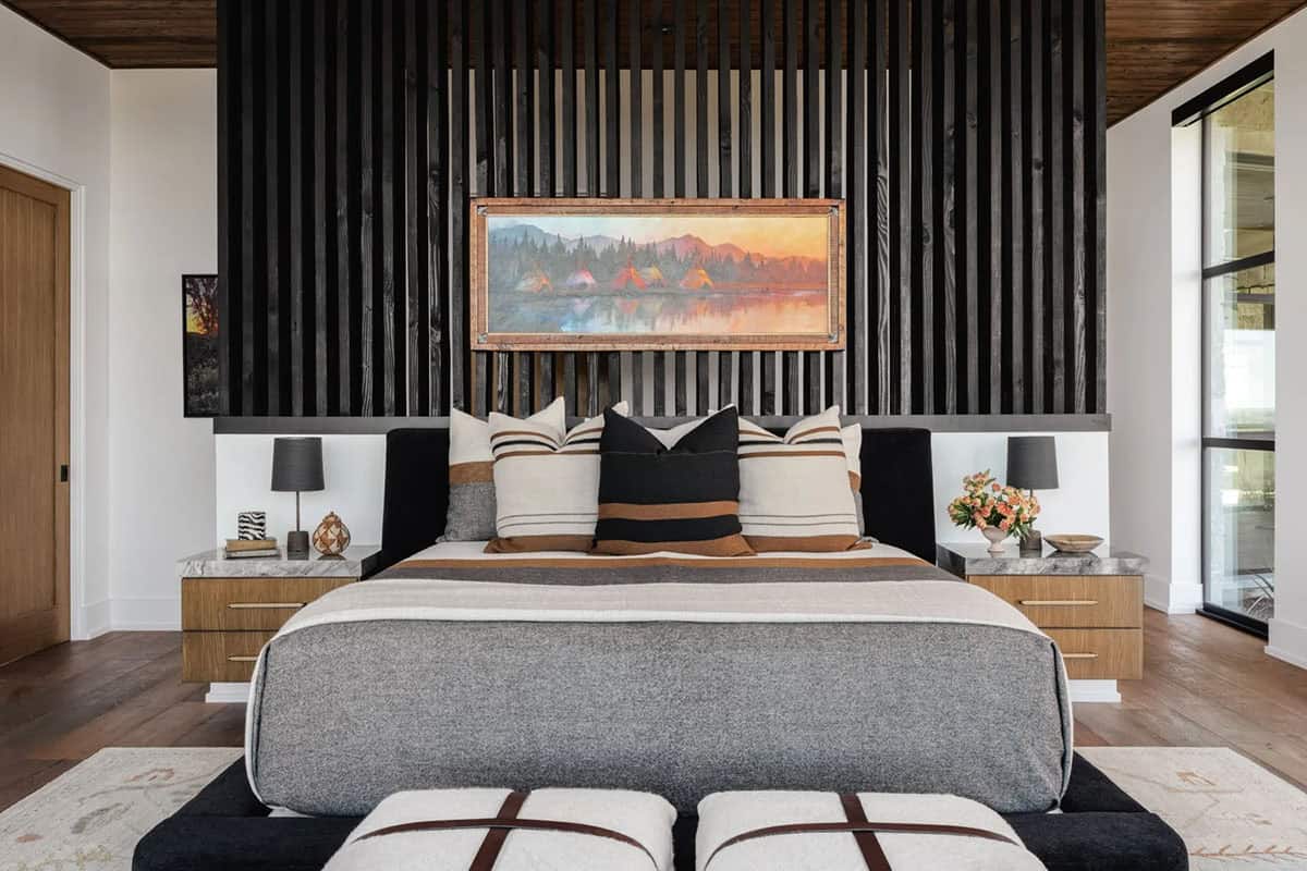 Primary bedroom with dark wood slat accent wall, striped pillows and landscape painting