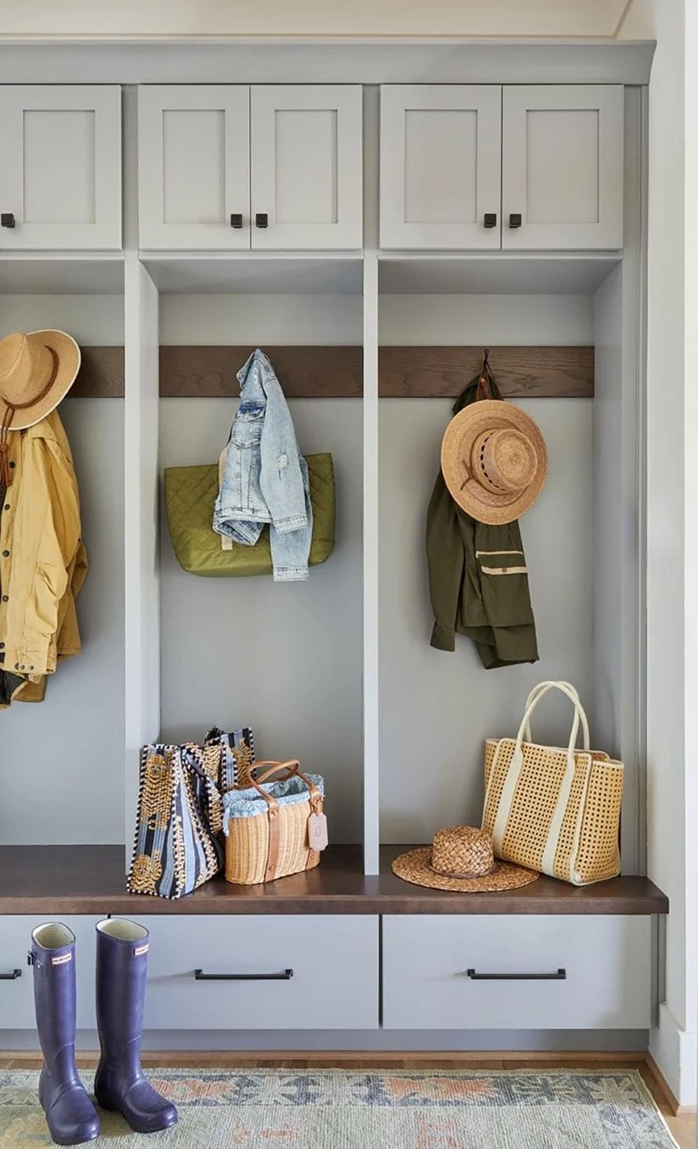 Built-in mudroom with gray shaker cabinets, walnut bench, coat hooks, and storage drawers