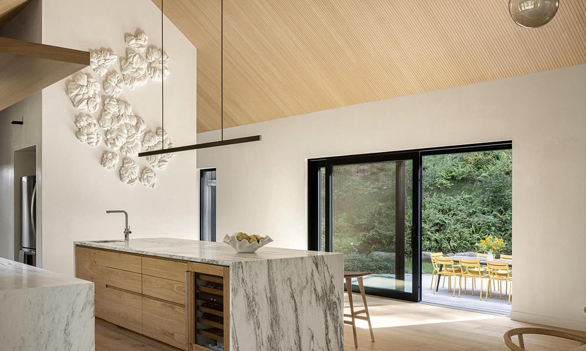 Kitchen island with marble waterfall edge and wine fridge, with sliding glass doors opening to an outdoor dining patio