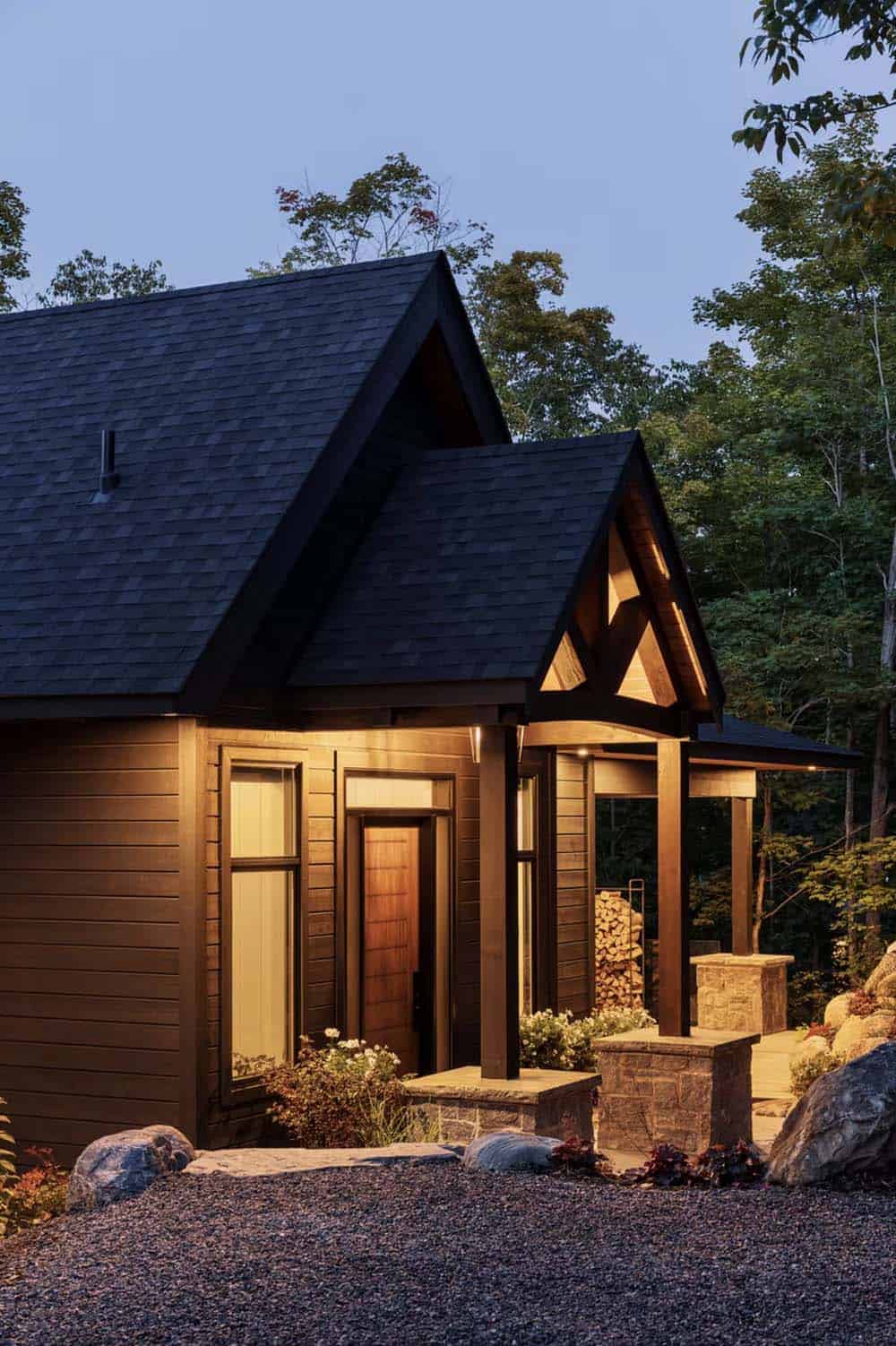 Cozy cottage entrance at night with wooden door, timber gable detail, and landscape lighting