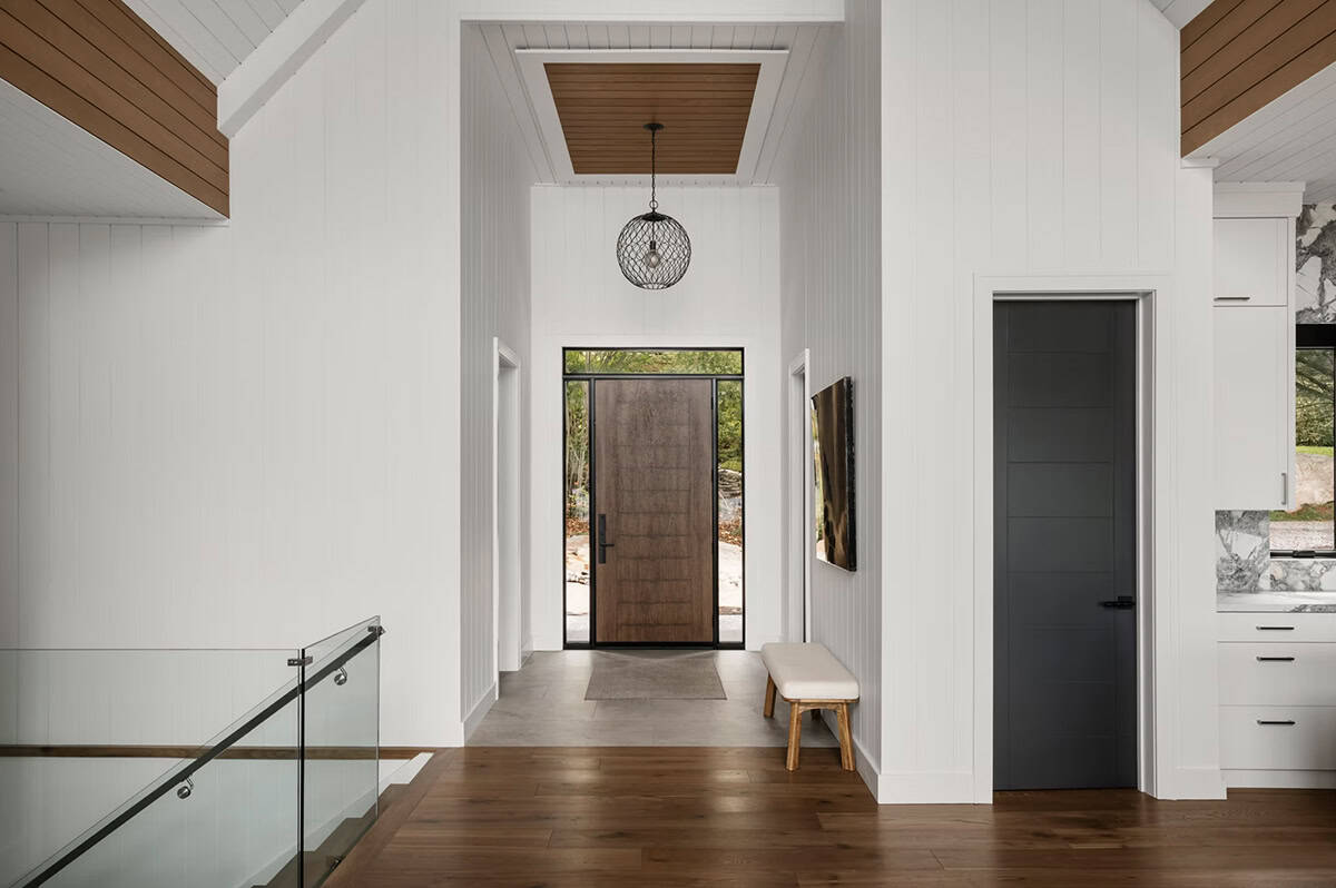 Bright cottage entryway with shiplap walls, wood ceiling inset, globe pendant light, and walnut front door
