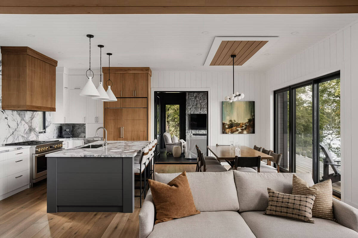 Open-plan kitchen and living area with wood cabinetry, marble island, and sliding doors to lake view