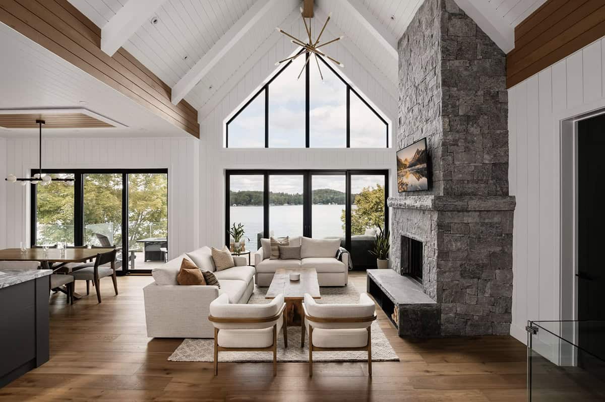Cathedral ceiling living room with dramatic lake view through gabled windows and stone fireplace