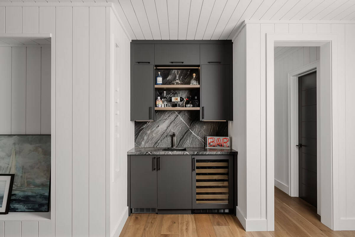 Built-in wet bar with dark cabinetry, dark marble backsplash, wine fridge, and neon bar sign