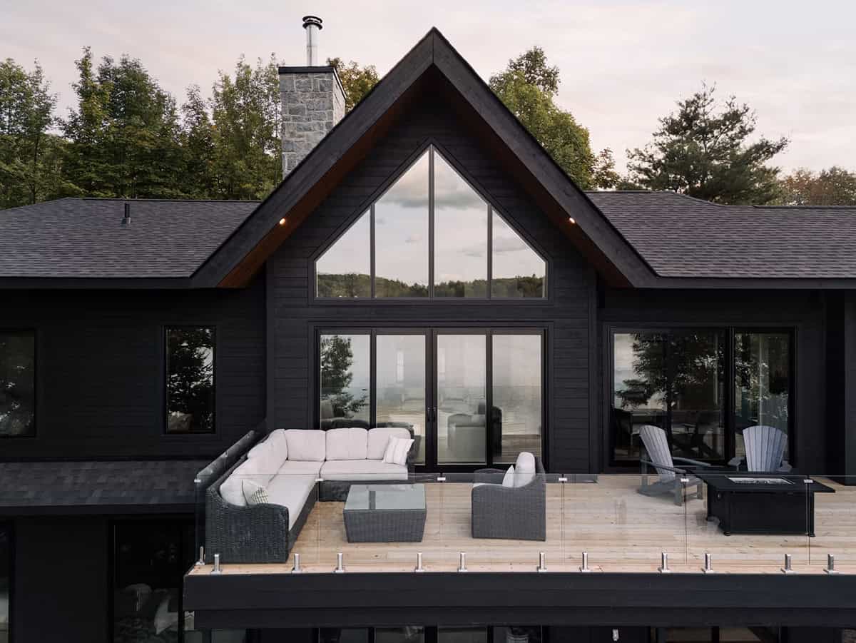 Cottage upper deck close-up with outdoor sectional, Adirondack chairs, fire table, and triangular gable window