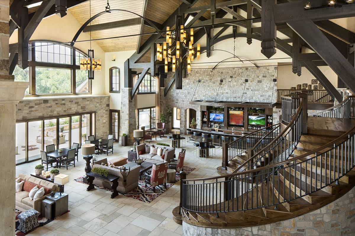 Aerial view of great room with structural wood trusses, bar, and curved staircase