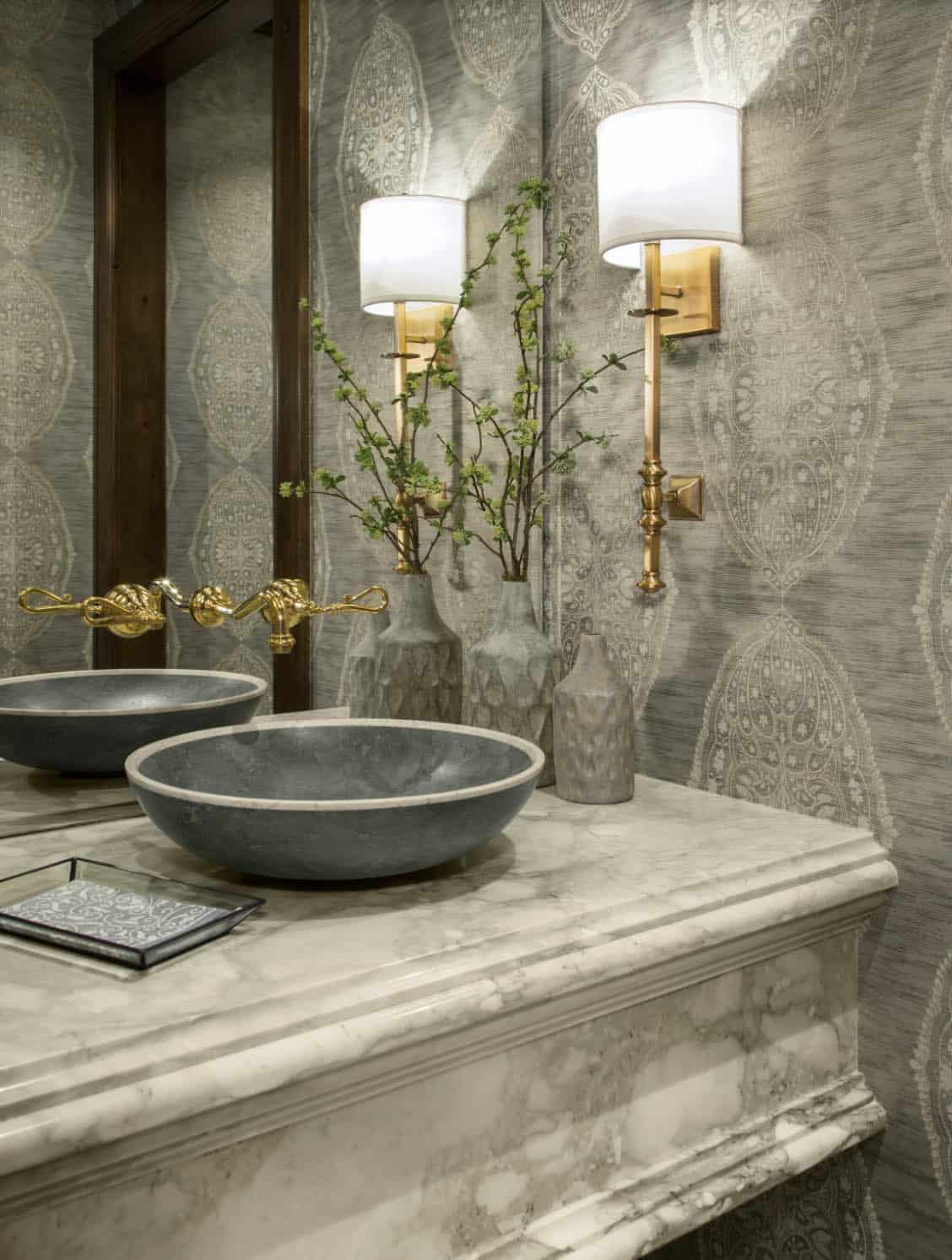 Powder room with stone vessel sinks, marble vanity, and gold fixtures