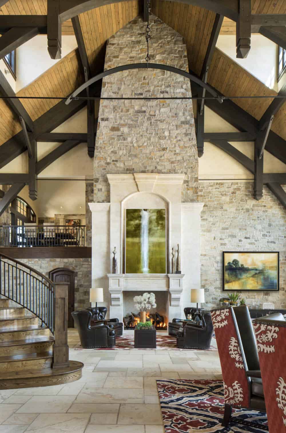 Soaring stone fireplace with cast stone surround beneath wood truss cathedral ceiling