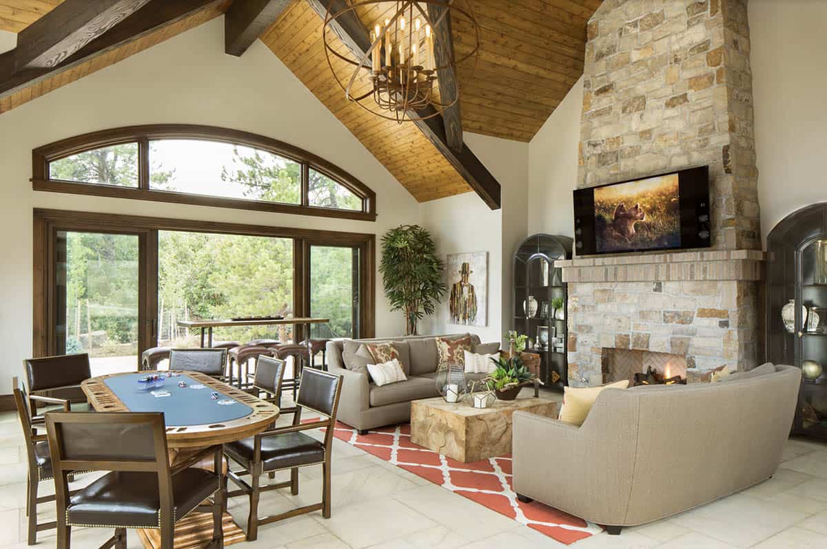 Pool house game room with poker table, stone fireplace, and vaulted wood ceiling
