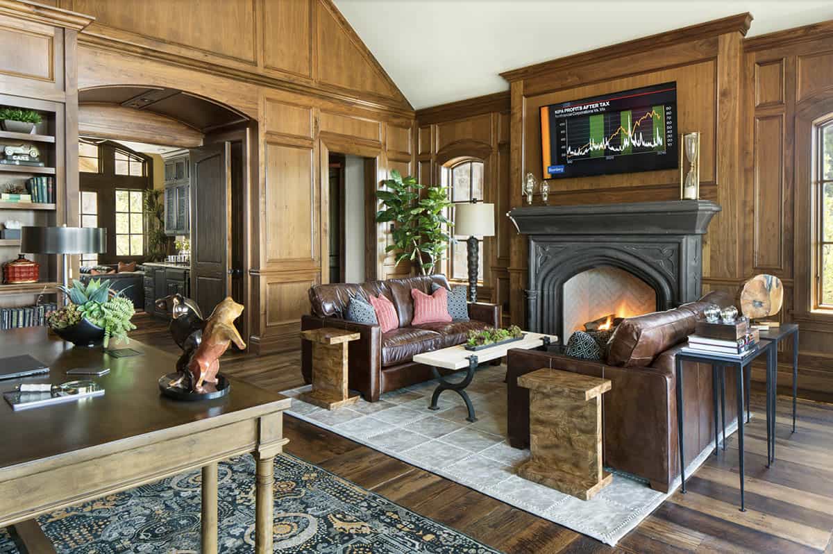 Executive home office with wood paneling, leather sofas, and ornate fireplace
