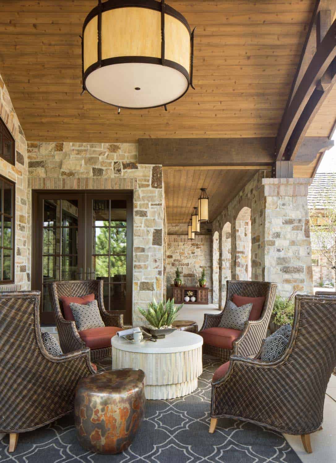 Covered front porch with wicker lounge chairs, wood ceiling, and pendant lantern