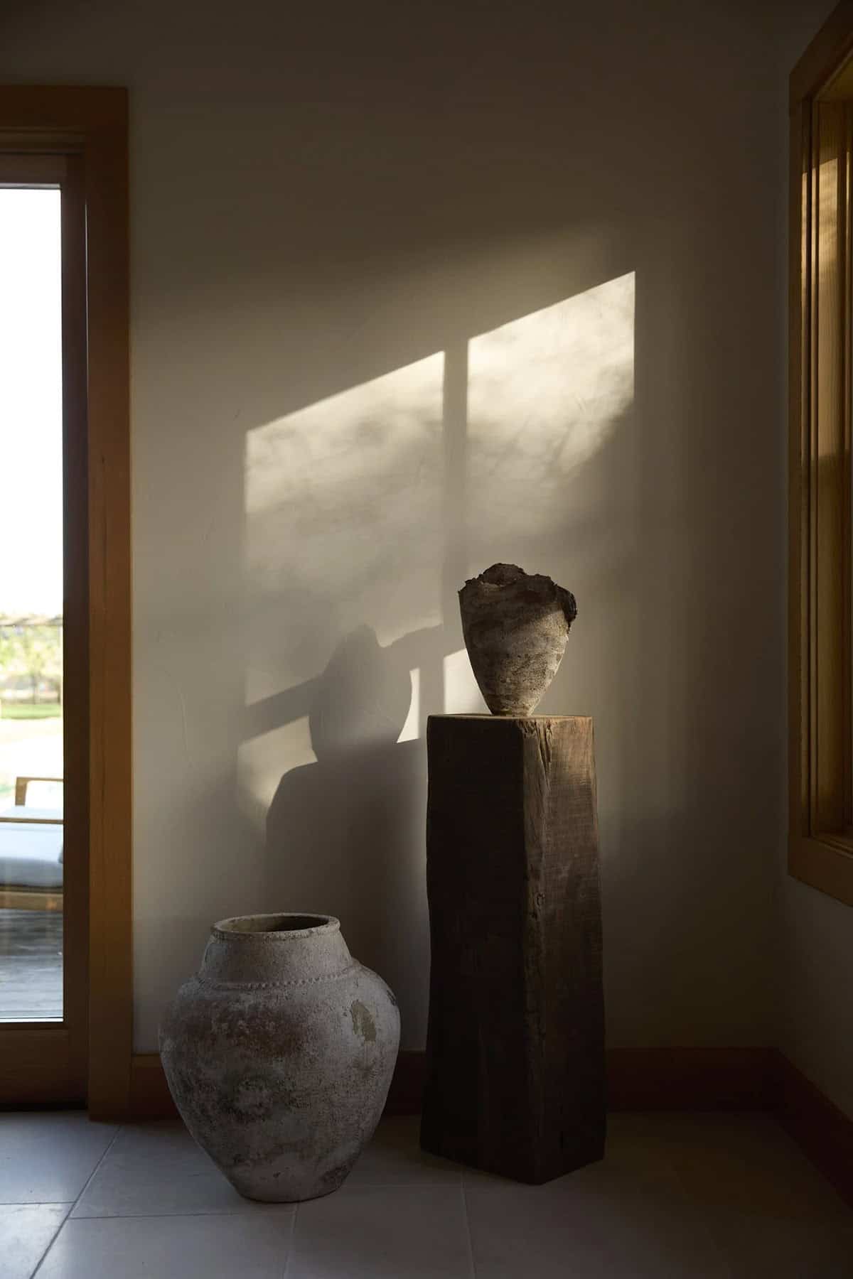 Rustic ceramic vessels with dramatic window light in California farmhouse