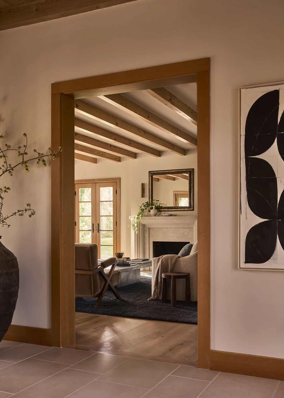 View through doorway into living room with stone fireplace and French doors