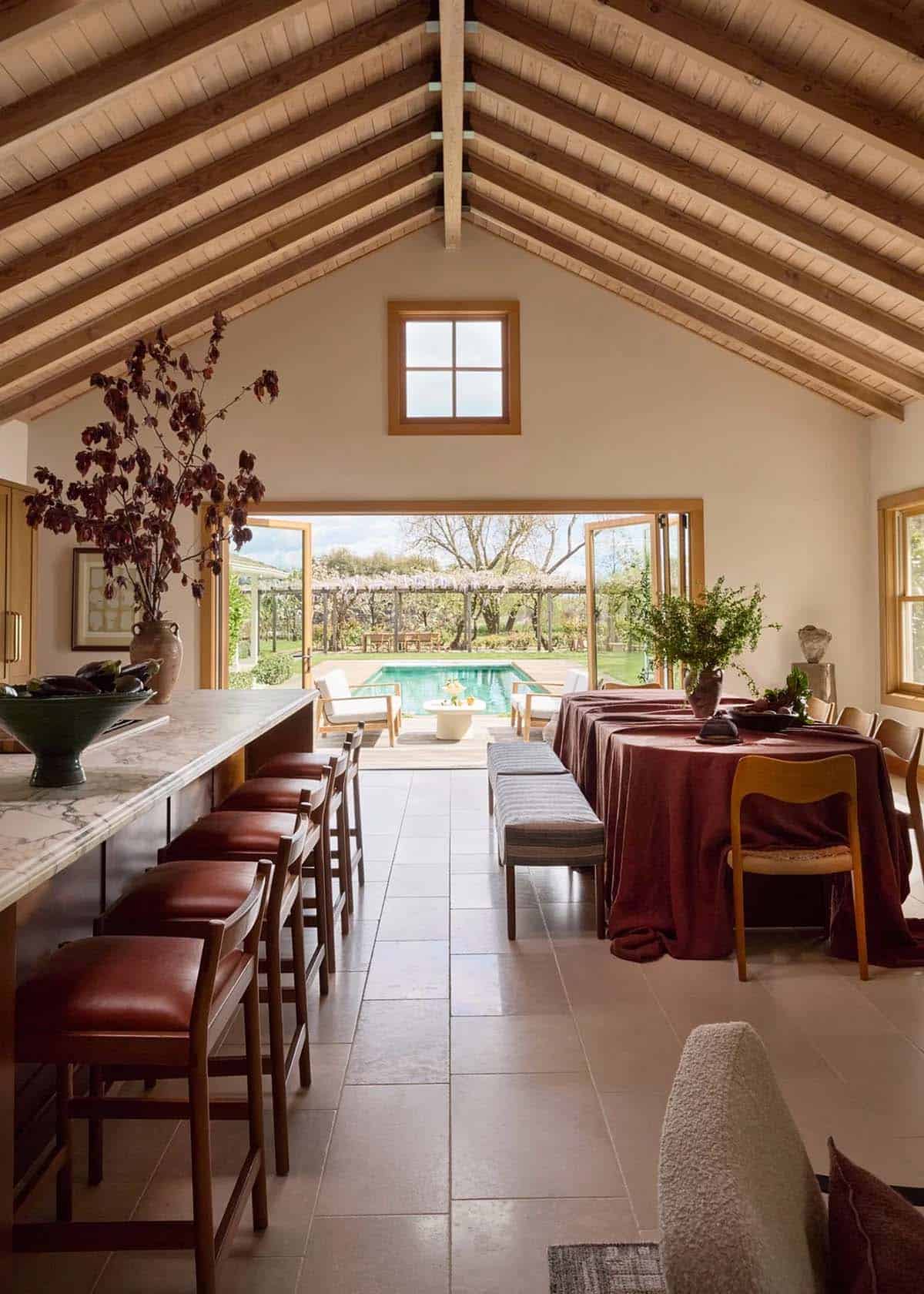Kitchen and dining room open to pool and wisteria pergola through folding doors