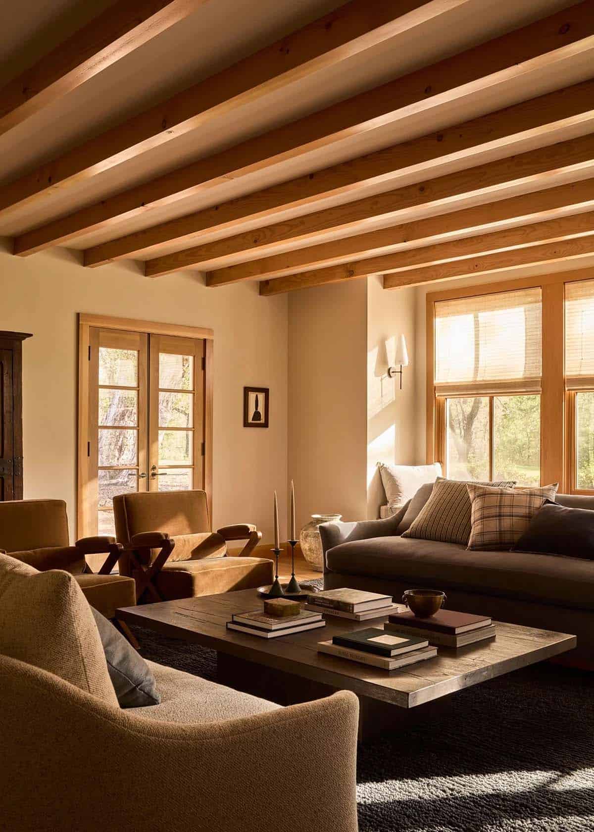 Cozy living room with cedar beam ceiling, velvet chairs, and woven shades