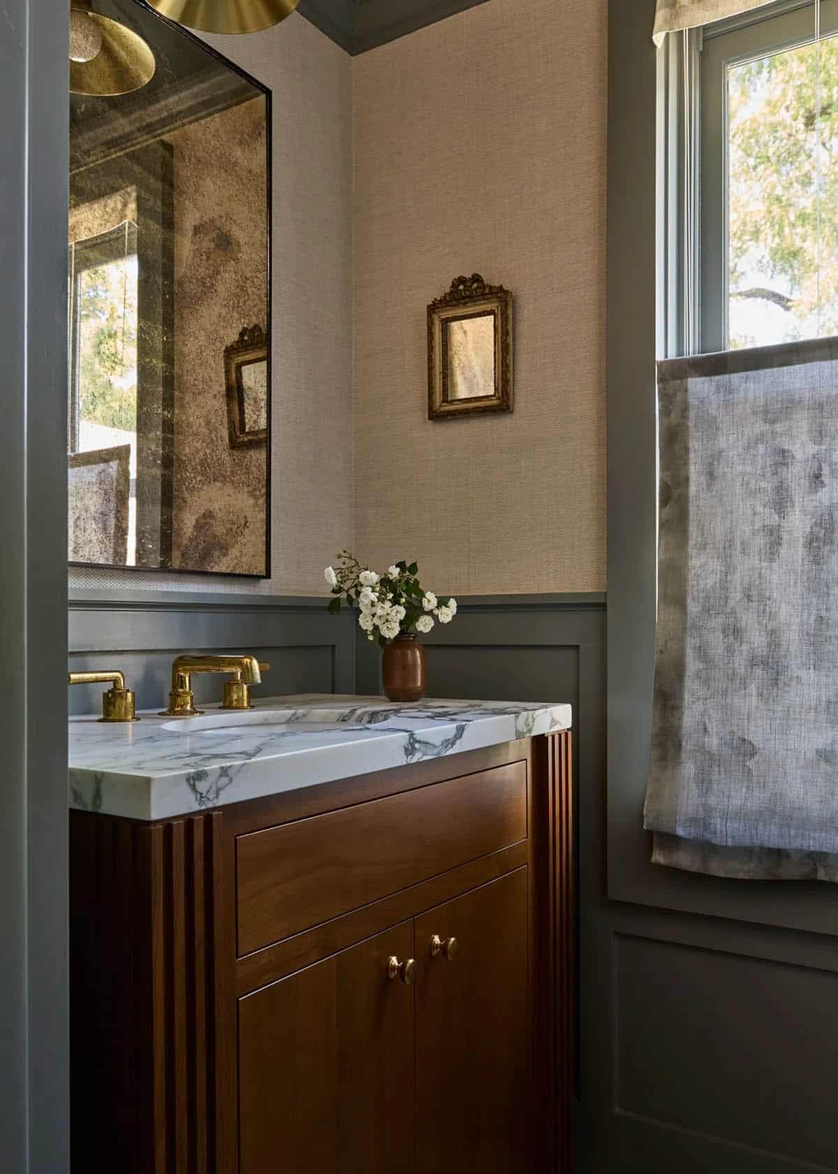 Powder room with grasscloth wallpaper, marble vanity, and brass fixtures