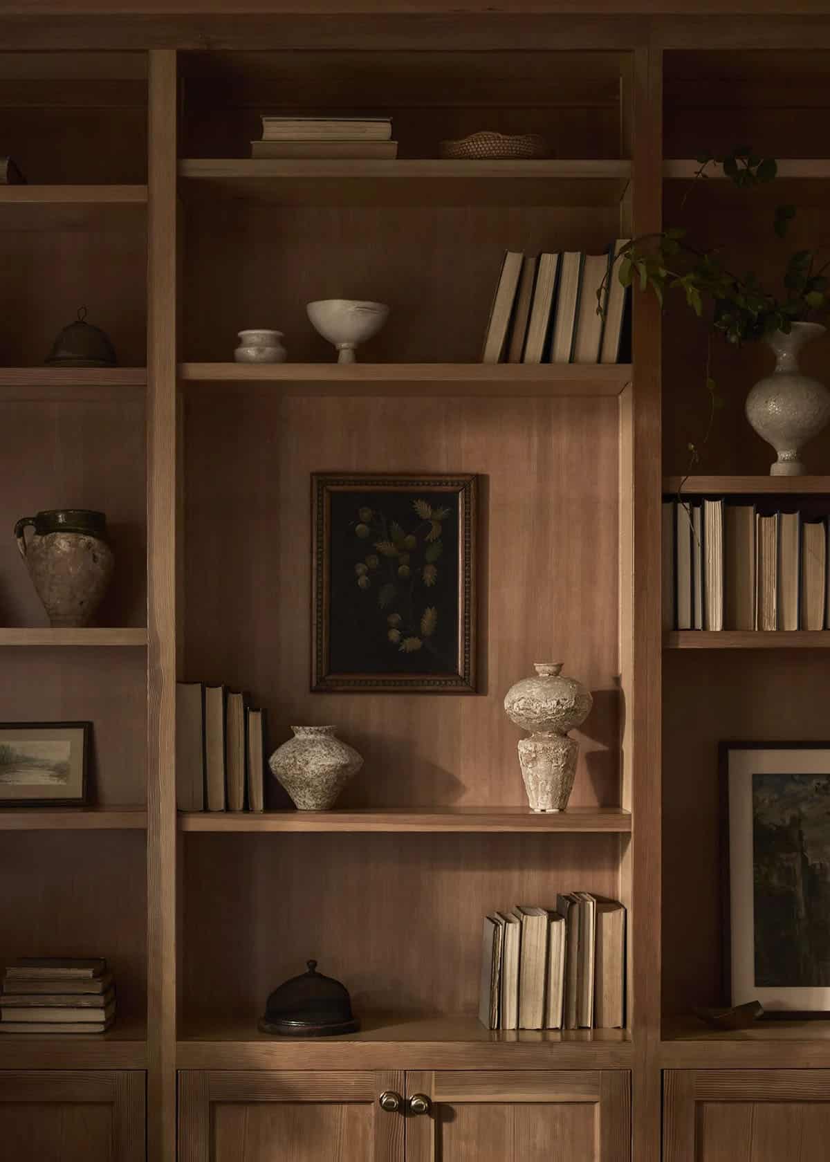 Styled walnut bookshelf with antique ceramics, vintage art, and books
