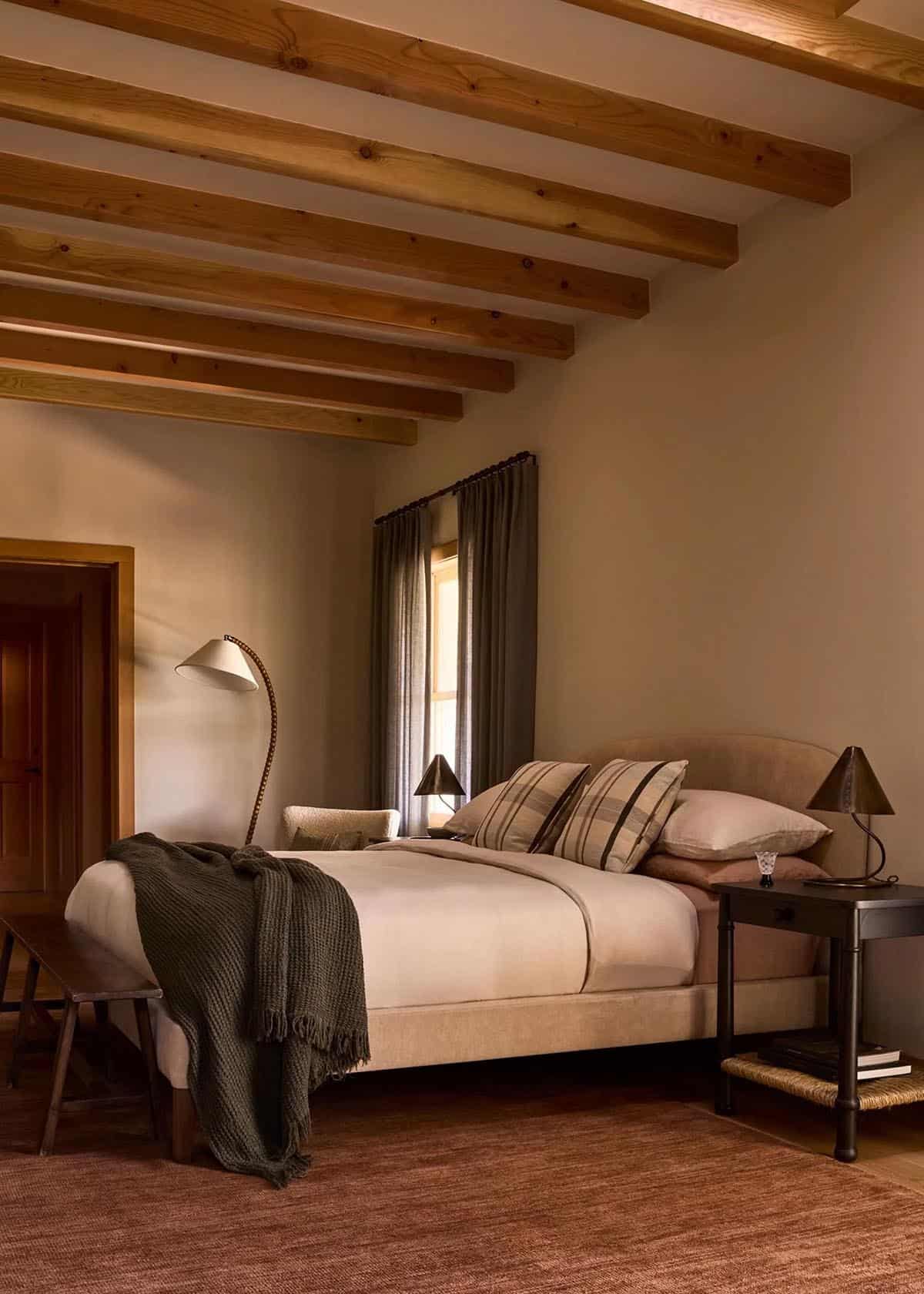 Primary bedroom with cedar beam ceiling, neutral linens, and earthy tones