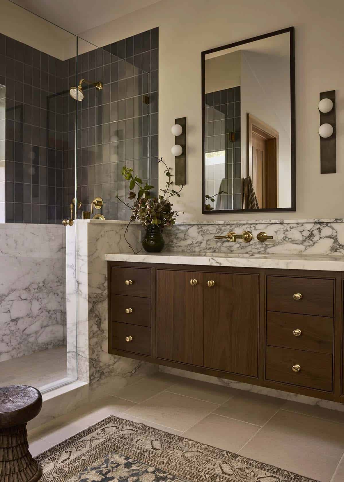 Primary bathroom with floating walnut vanity, marble backsplash, and dark tile shower