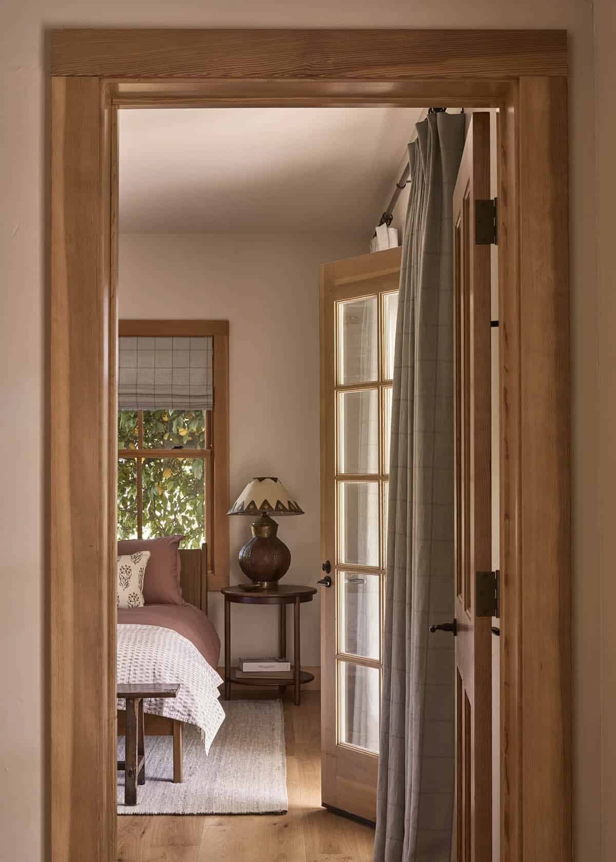 View through oak-framed doorway into guest bedroom with pink bedding