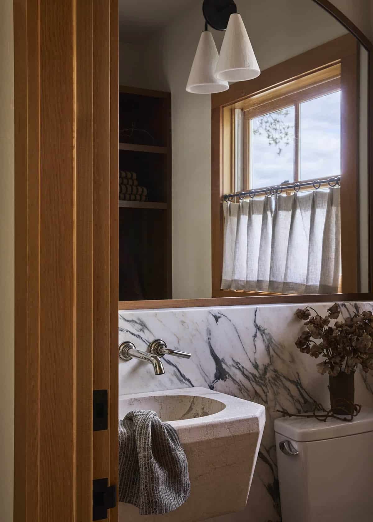 Kids bathroom with carved stone sink, marble backsplash, and linen cafe curtain