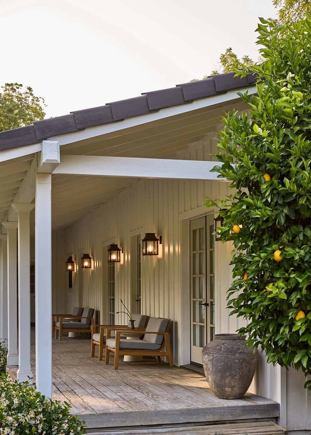 Covered back porch with teak chairs, lantern sconces, and lemon tree