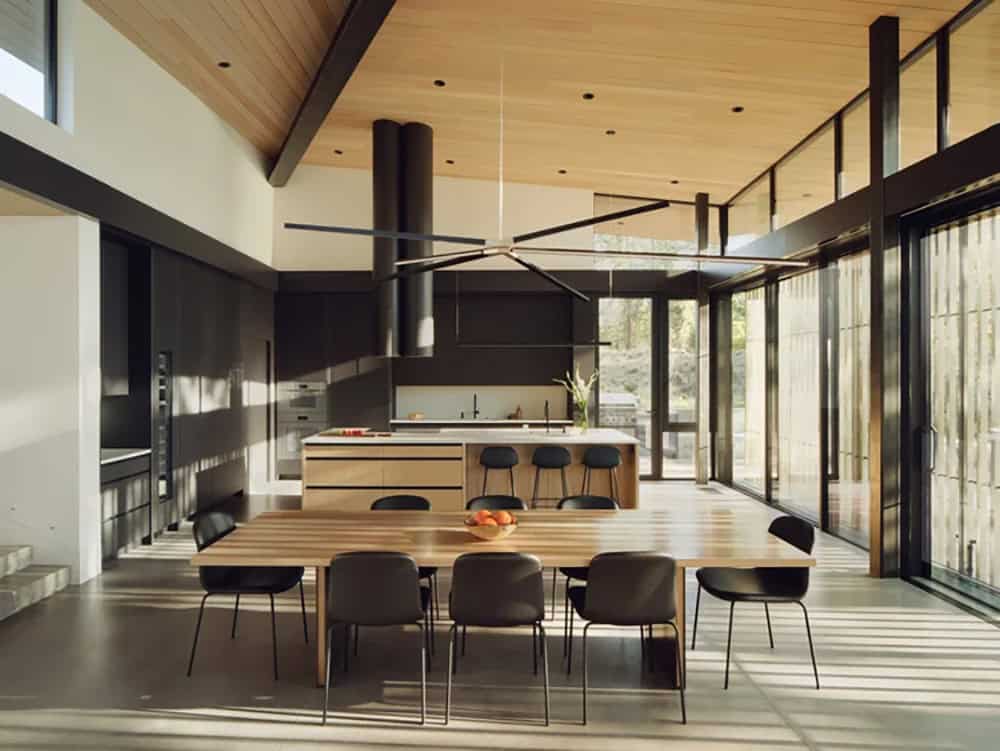 Spacious open-plan kitchen and dining area with vaulted wood ceiling, black island, and large ceiling fan
