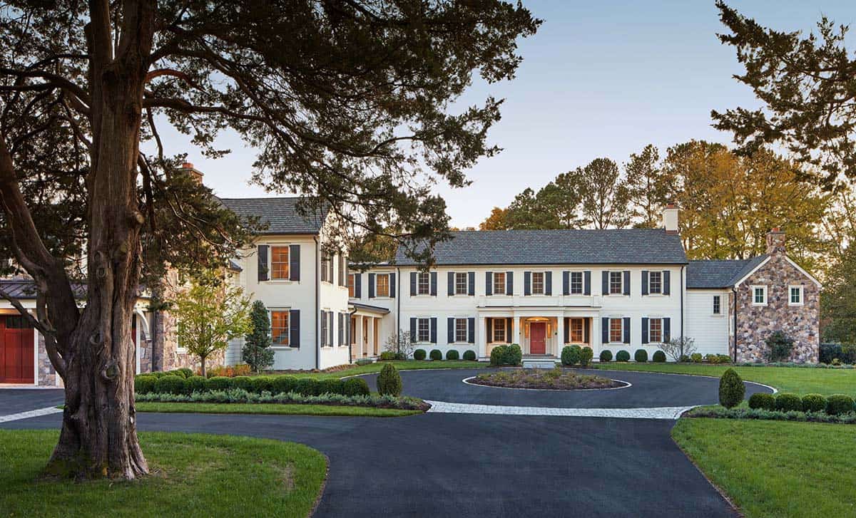 Historic waterfront house renovation with white painted brick, black shutters, red door and circular driveway on the Chesapeake Bay in Maryland