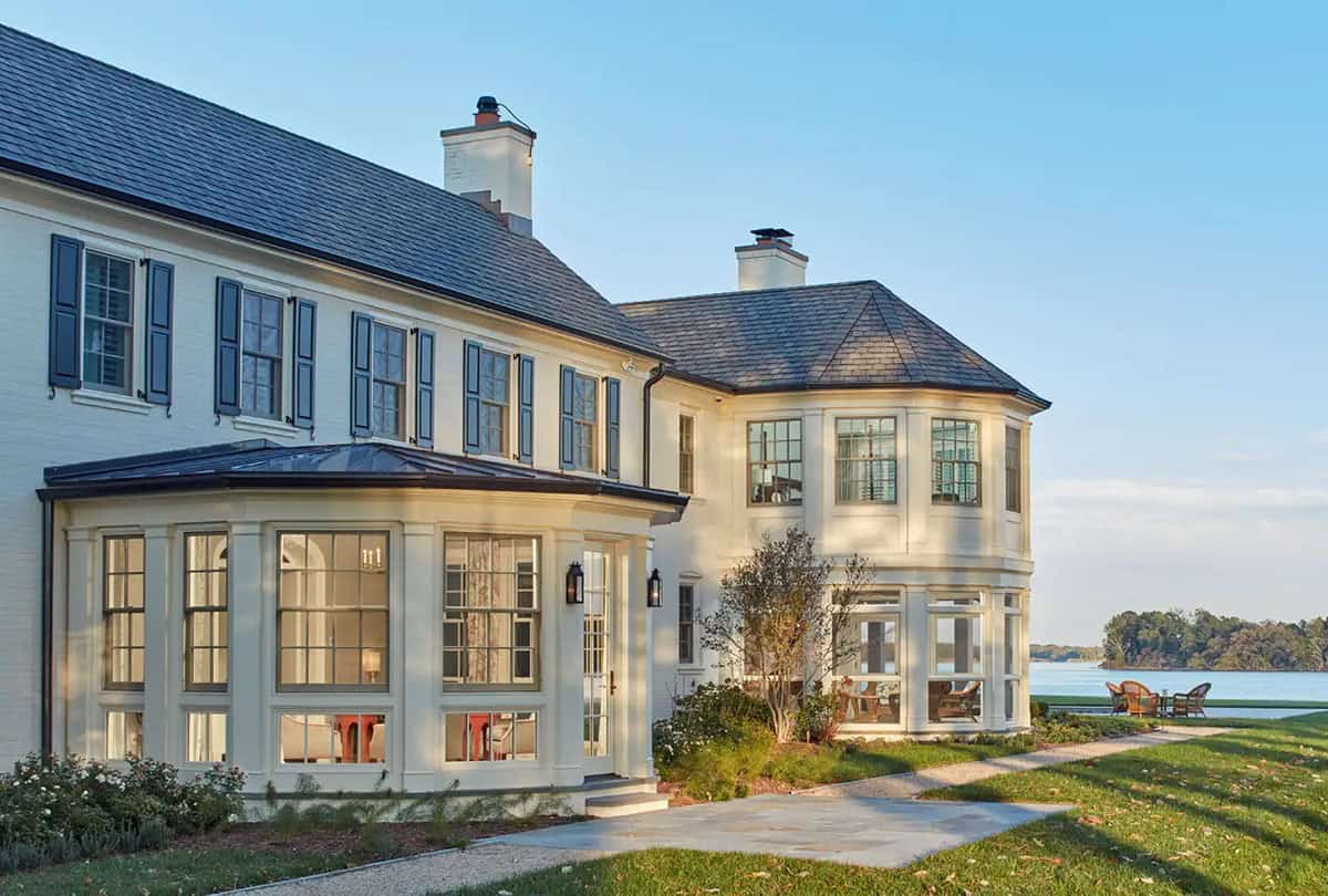 Historic waterfront house renovation with one-story faceted sunroom and bay windows overlooking the Chesapeake Bay in Maryland