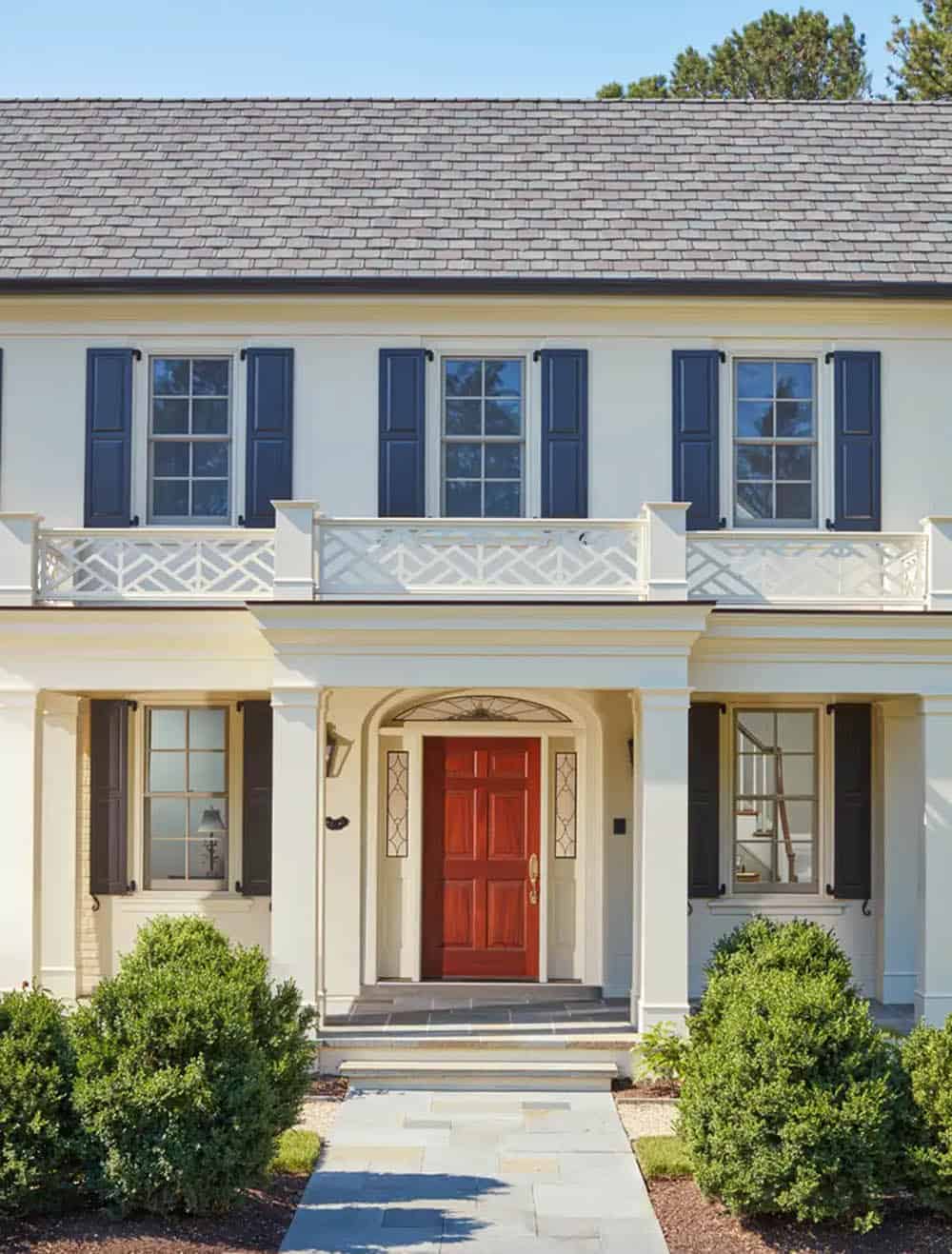 Historic waterfront house renovation front entry with red door, arched transom, decorative balcony railing and navy shutters in Maryland