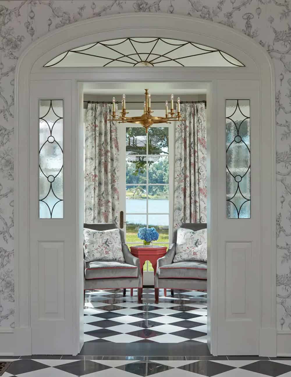 Historic waterfront house foyer with chinoiserie wallpaper, black and white diamond marble floor and brass chandelier in Maryland