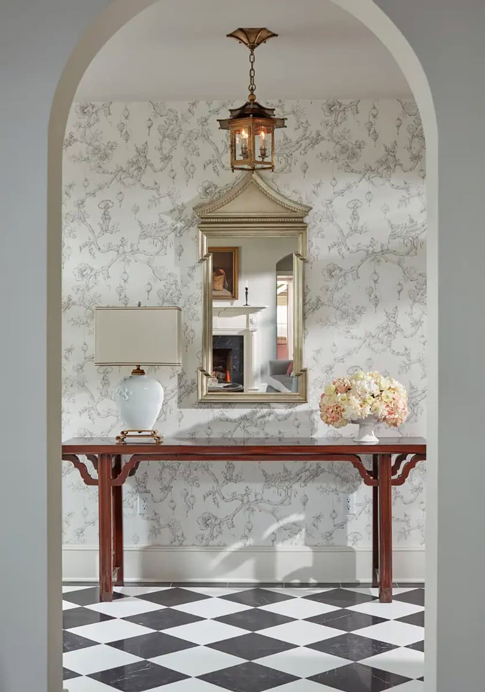 Historic waterfront house entry hall with chinoiserie wallpaper, Chinese console table, pagoda mirror and black and white diamond marble floor in Maryland