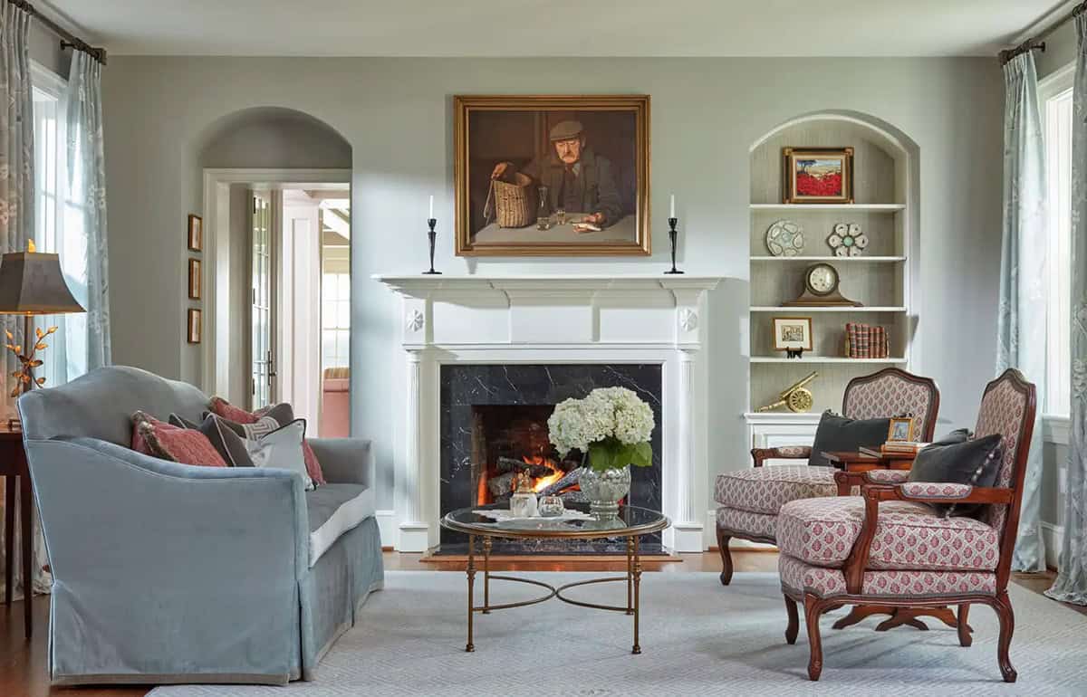 Historic waterfront house formal living room with marble fireplace, custom built-in shelving and French armchairs in Maryland