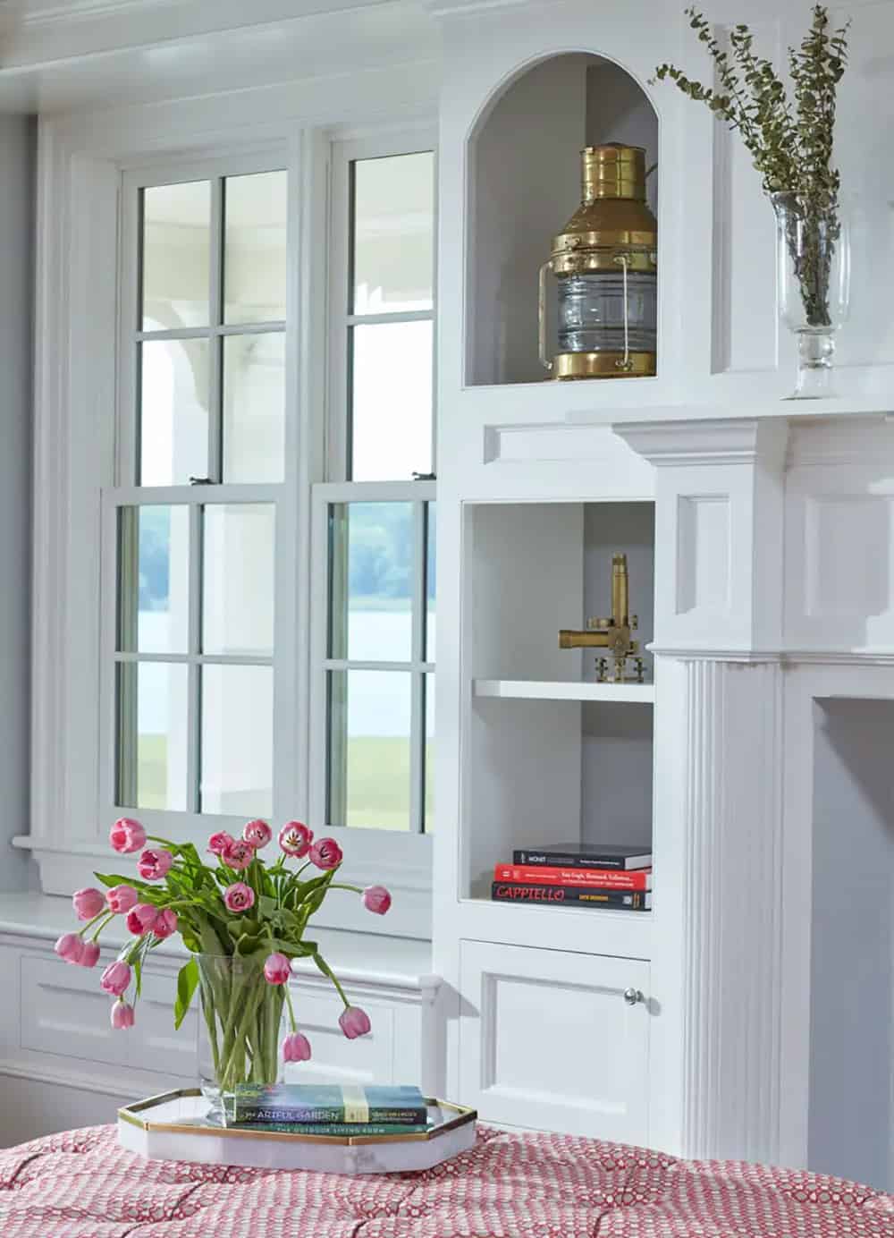 Historic waterfront house sunroom detail with custom built-in shelving, arched niche, brass nautical lantern and Chesapeake Bay views in Maryland