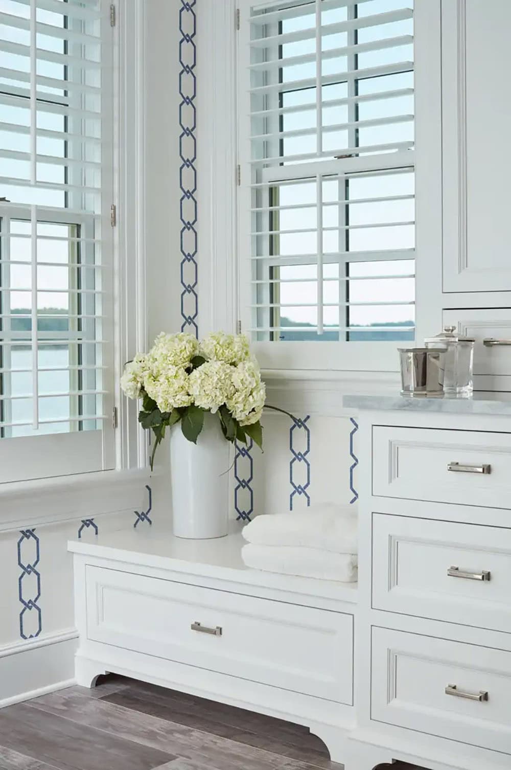 Historic waterfront house primary bathroom with white cabinetry, blue chain link wallpaper detail and Chesapeake Bay views in Maryland