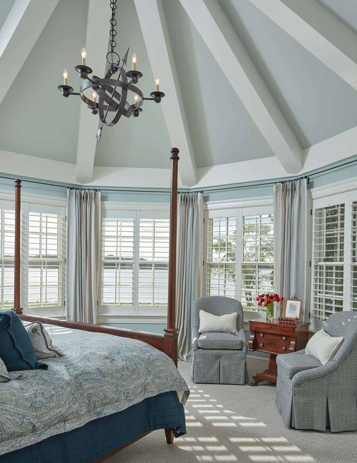 Historic waterfront house primary bedroom with vaulted octagonal ceiling, four-poster bed, iron chandelier and wraparound bay windows in Maryland