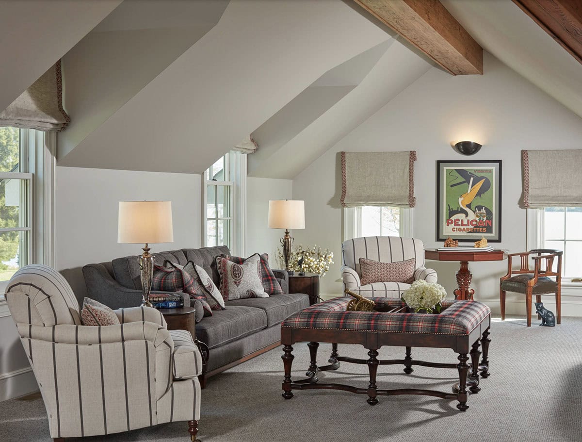Historic waterfront house upper sitting room with vaulted ceiling, exposed wood beam, plaid ottoman and Chesapeake Bay views in Maryland