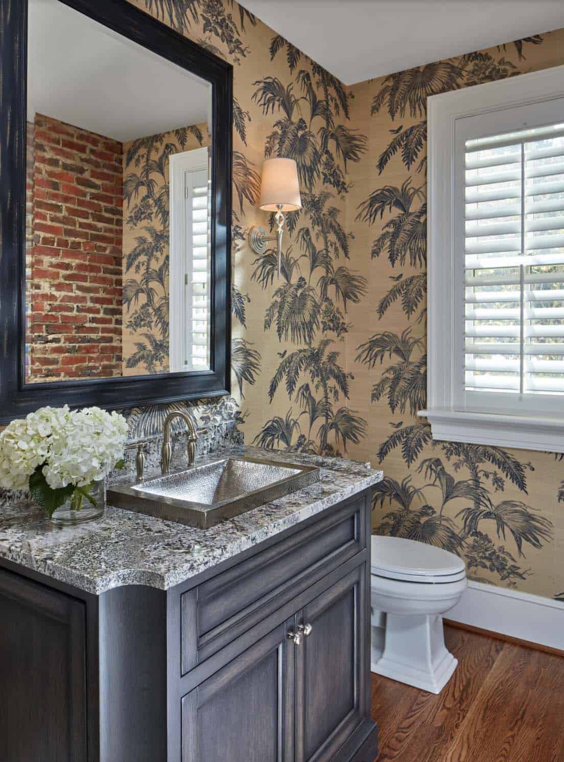Historic waterfront house powder room with tropical toile wallpaper, exposed brick wall, hammered silver sink and granite vanity in Maryland