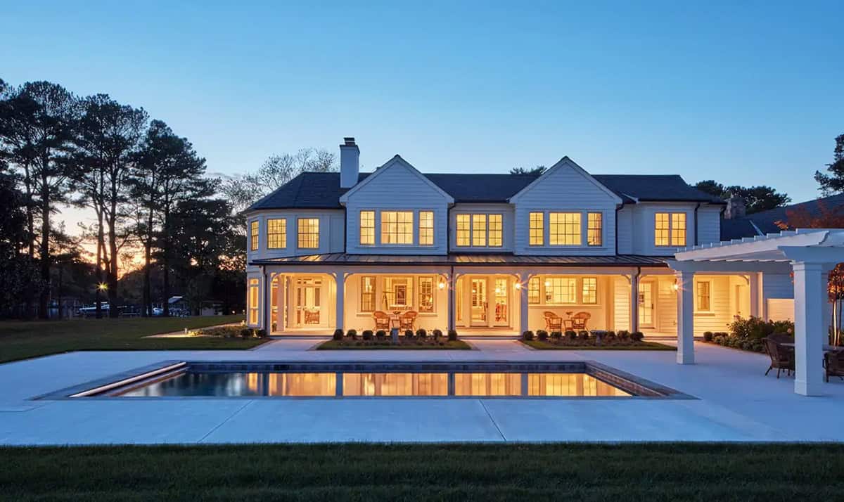 Historic waterfront house rear exterior with screened porch, pool and pergola at dusk on the Chesapeake Bay in Maryland
